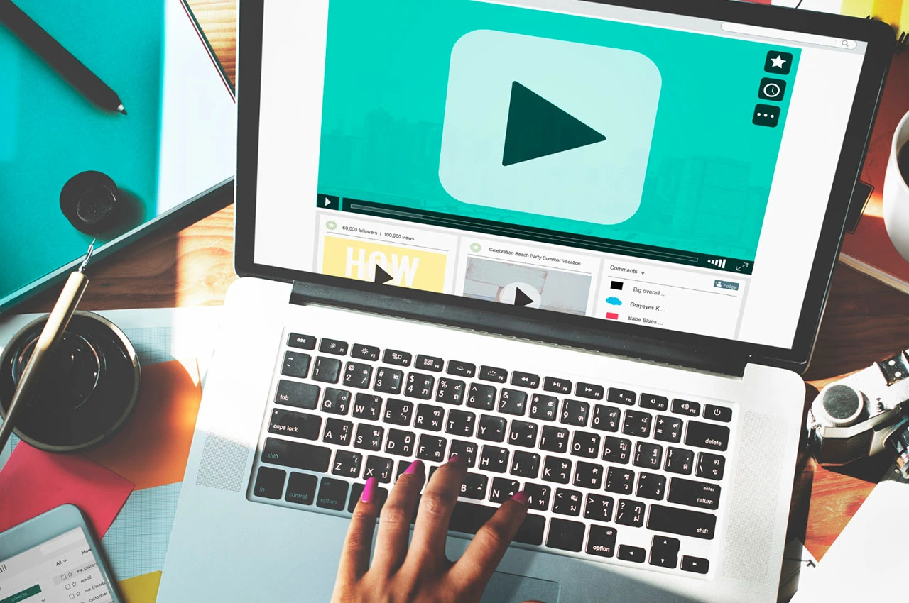 Laptop showing video play button representing uploading and selling videos online
